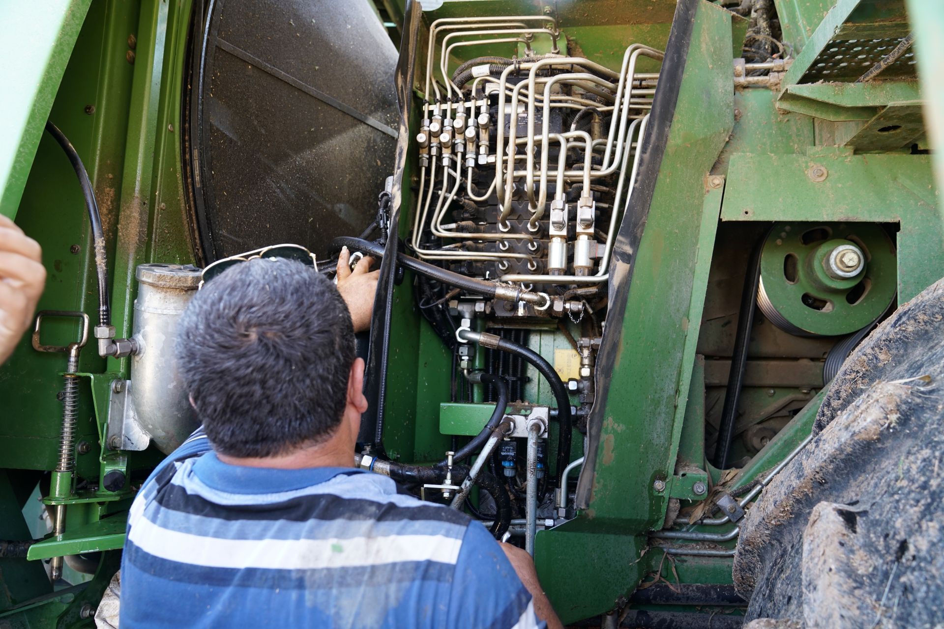 Landwirt bei Wartung einer Traktorhydraulik – Anwendung hydraulischer Geraetebetaetigung in der Landwirtschaft